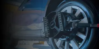 Close-up of a car wheel with mounted vibration measurement equipment in a workshop.