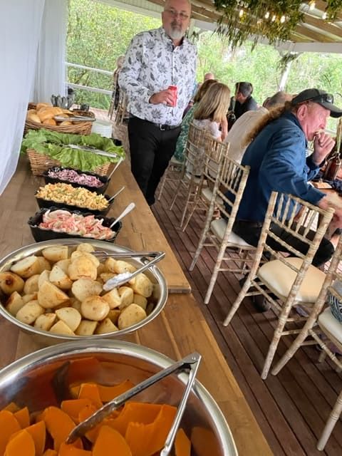 A Group Of People Are Sitting At A Table With Bowls Of Food — Tru Blu Catering In Port Macquarie, NSW