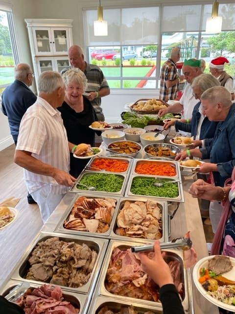 A Group Of People Are Standing Around A Buffet Table Eating Food — Tru Blu Catering In Lake Cathie, NSW