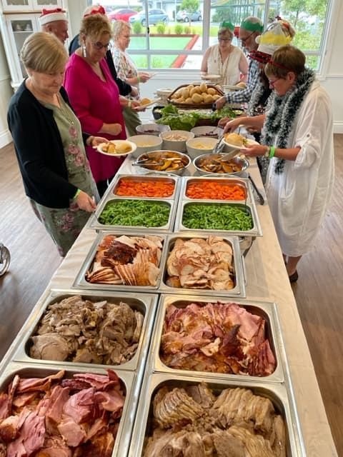 A Group Of People Are Standing Around A Buffet Table Filled With Food — Tru Blu Catering In Lake Cathie, NSW