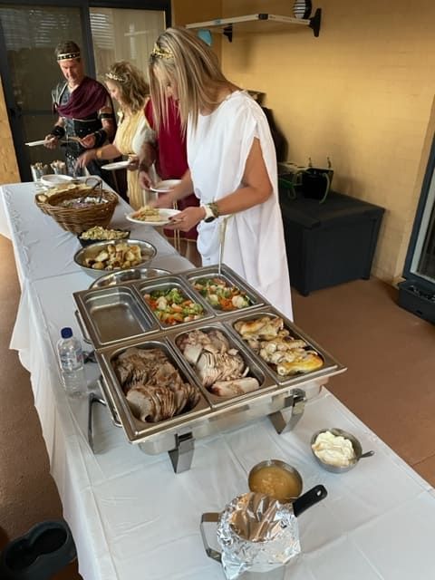 A Woman In A White Dress Is Standing At A Buffet Table — Tru Blu Catering In Coffs Harbour, NSW