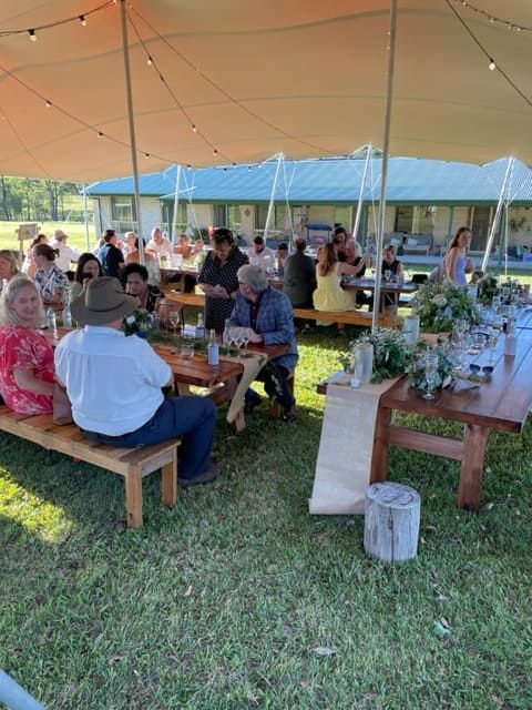 A Group Of People Are Sitting At Tables Under A Tent — Tru Blu Catering In Nambucca, NSW