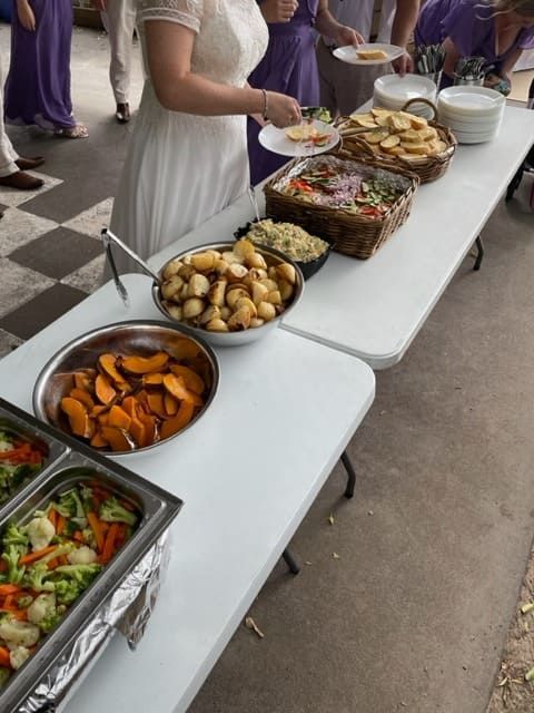 A Woman In A White Dress Is Standing In Front Of A Table Full Of Food — Tru Blu Catering In Kempsey, NSW