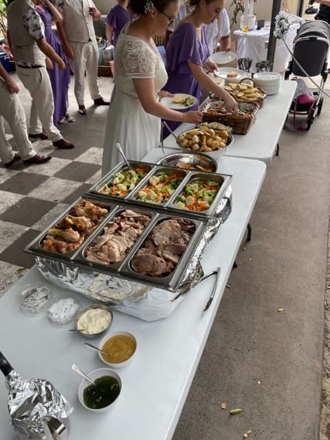 A Woman In A White Dress Is Standing In Front Of A Table Full Of Food — Tru Blu Catering In Kempsey, NSW