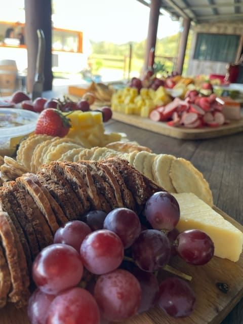 A Wooden Cutting Board With Grapes Cheese And Crackers On It — Tru Blu Catering In Kempsey, NSW