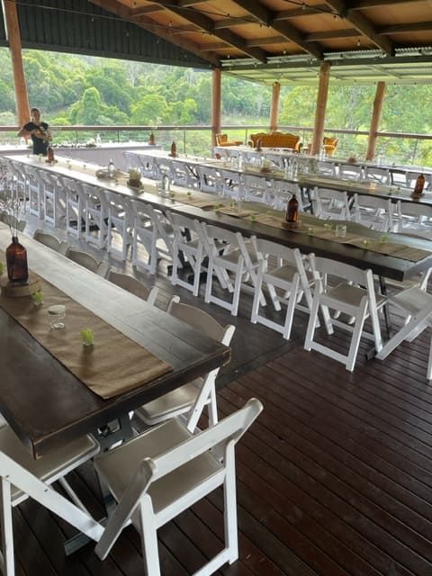 A Row Of Tables And Chairs On A Wooden Deck — Tru Blu Catering In Kempsey, NSW