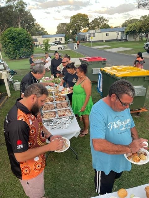 A Group Of People Are Standing Around A Table Eating Food — Tru Blu Catering In Port Macquarie, NSW
