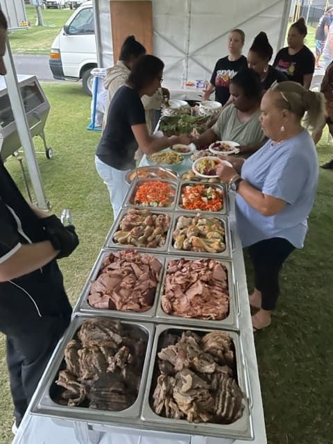 A Group Of People Are Standing Around A Table With Trays Of Food — Tru Blu Catering In Wauchope, NSW