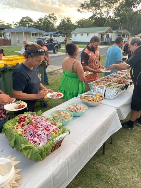 A Group Of People Are Standing Around A Table With Food On It — Tru Blu Catering In Port Macquarie, NSW
