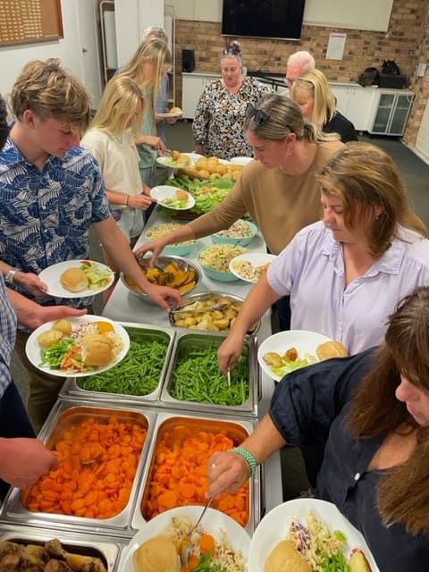 A Group Of People Are Getting Food From A Buffet Line — Tru Blu Catering In Port Macquarie, NSW