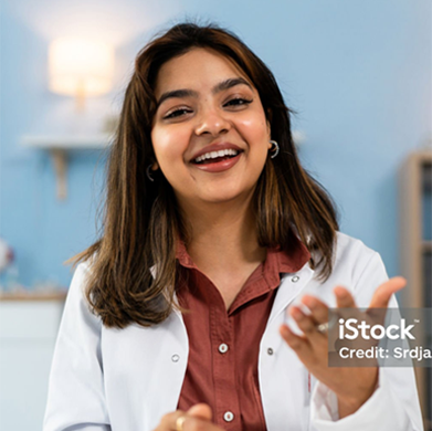 Smiling doctor in a white coat speaking in a bright clinic setting