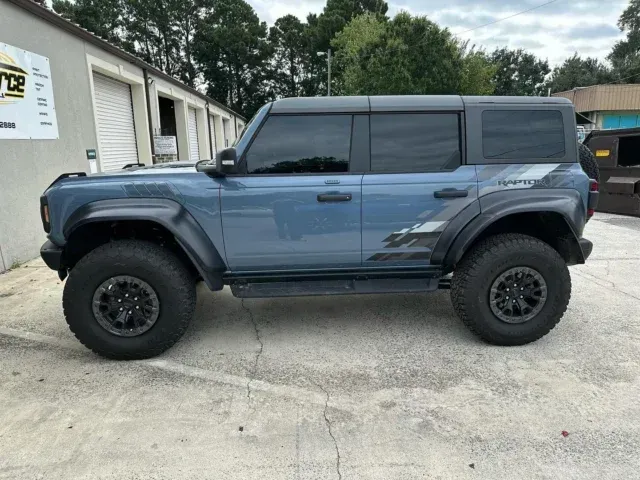 Blue lifted SUV parked beside a building, viewed from the side