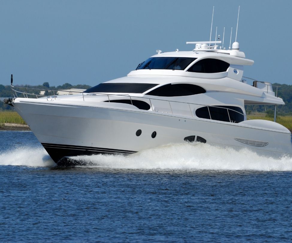 White luxury yacht speeding across blue water, creating a spray wake under a clear sky