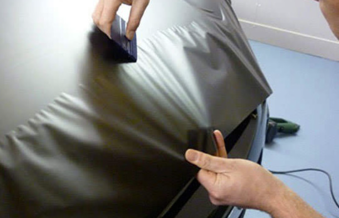 Hand using a small brush to clean a gray fabric-covered chair or cushion indoors