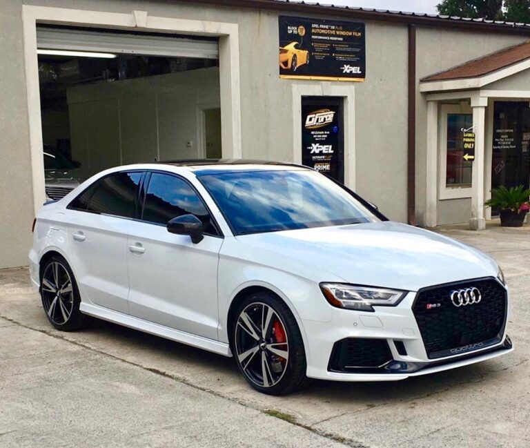 White Audi sedan parked outside a building, front three-quarter view