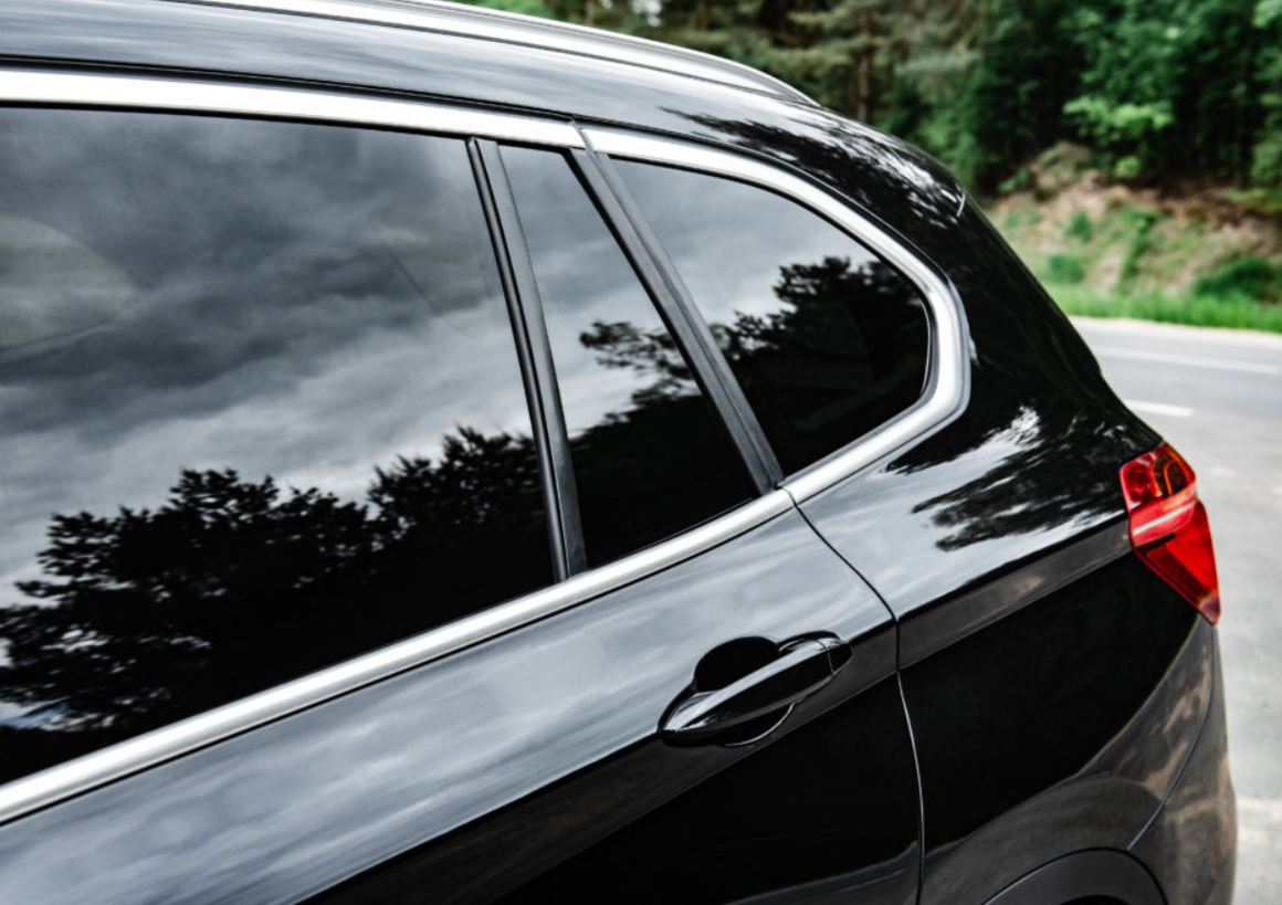 Close-up of a black SUV’s side windows and rear door with tinted glass and red taillight