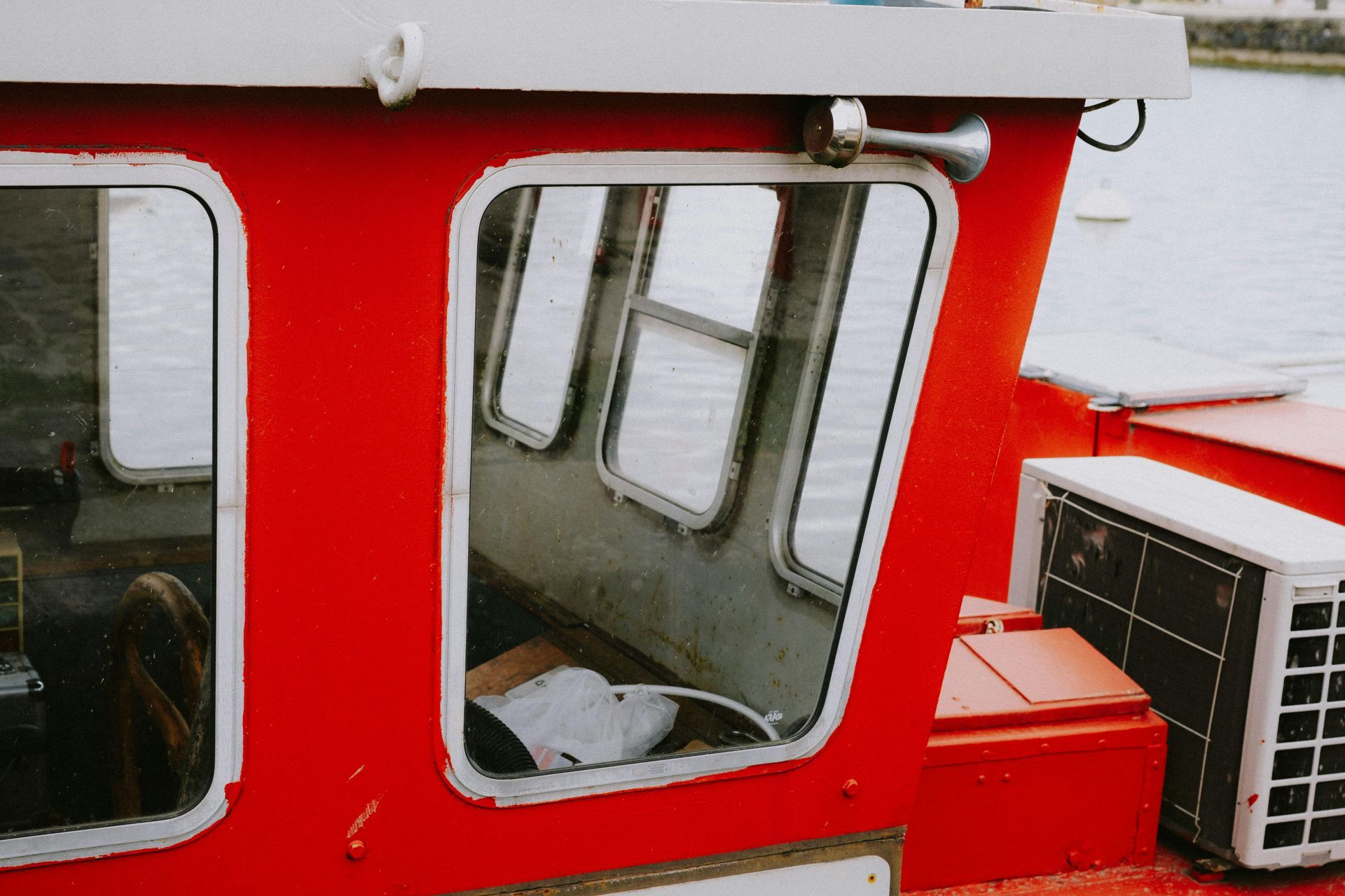 Red and white boat cabin windows with an air conditioner unit on the right side
