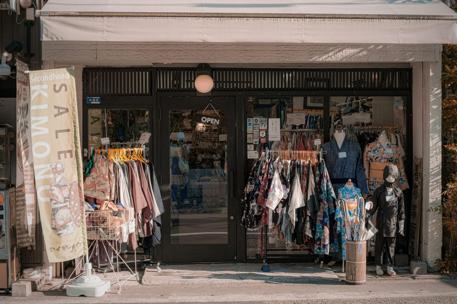 Clothing shop storefront with racks of colorful garments displayed outside and inside.