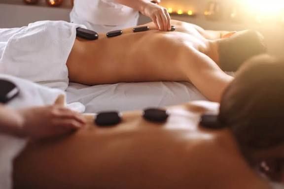 Hot stone massage on a person’s back with therapist’s hands in a spa setting