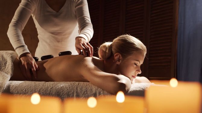 Person receiving a spa massage on a table, with candles glowing in the foreground