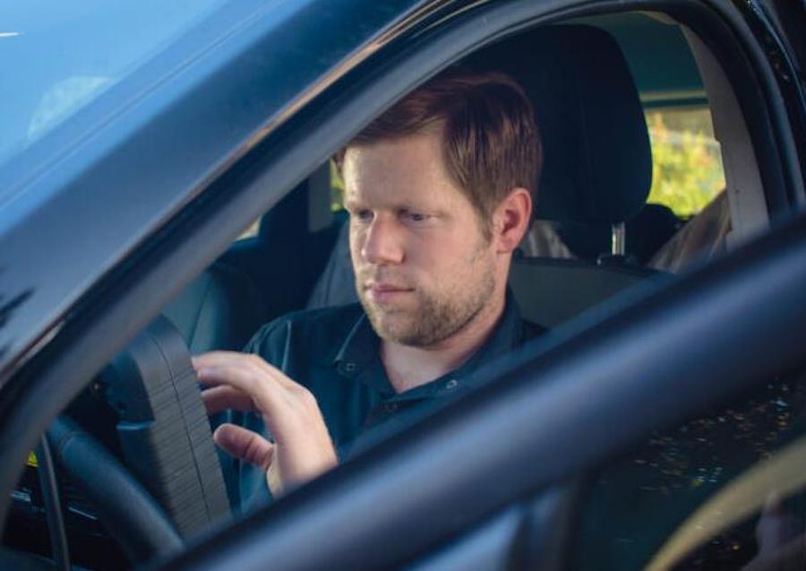 A man is sitting in the driver 's seat of a car.