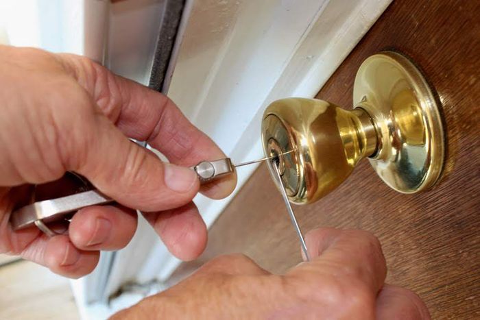 A person is fixing a door lock with a screwdriver.