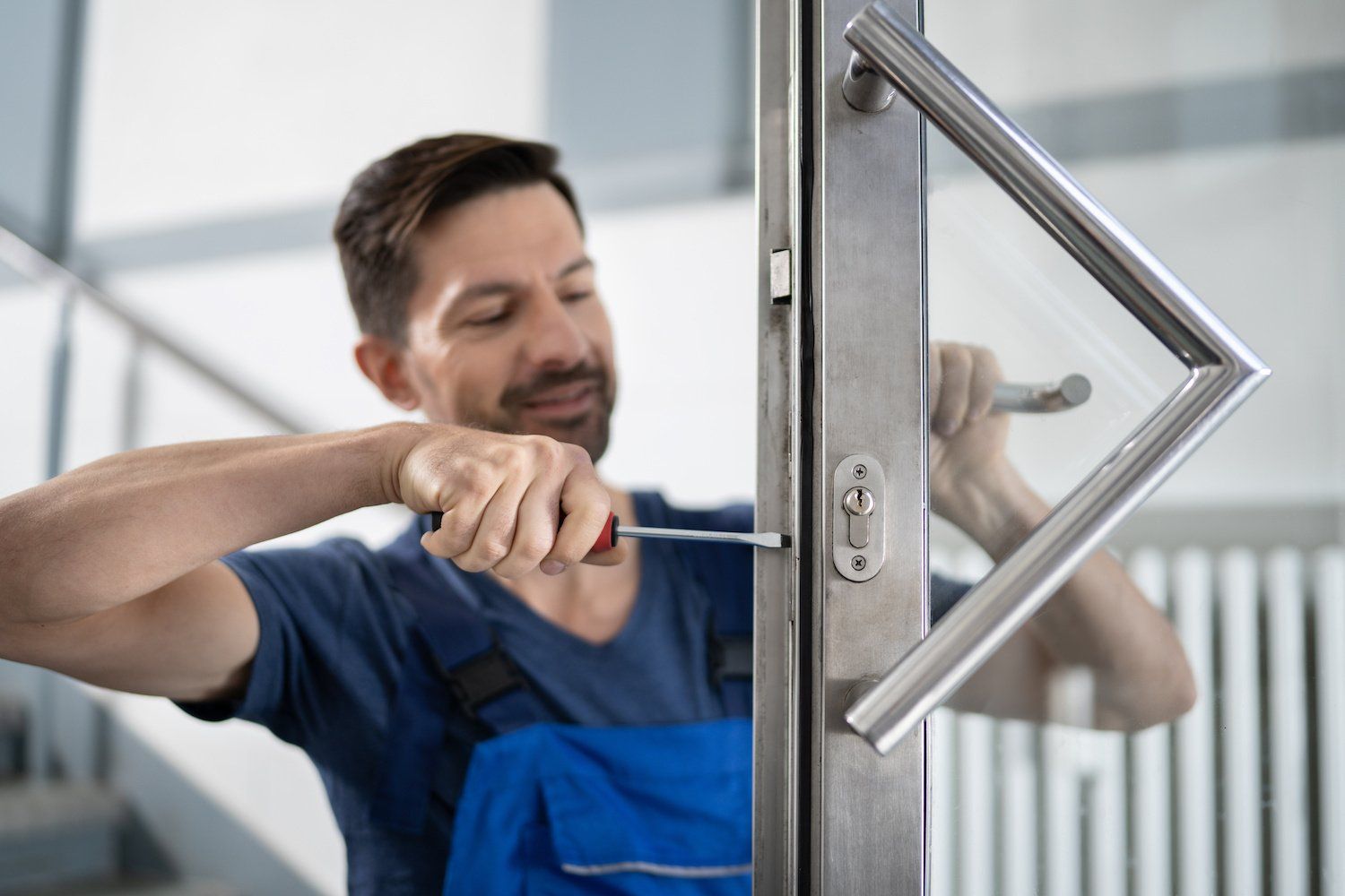 A man is fixing a door with a screwdriver.
