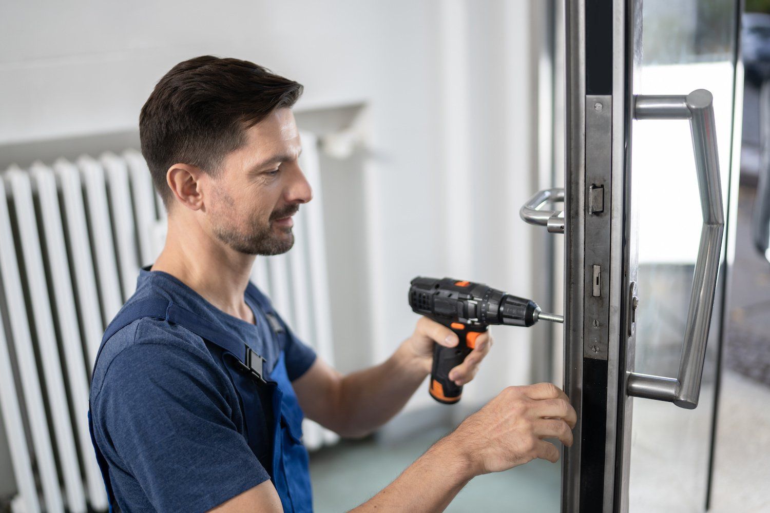 A man is fixing a door with a drill.