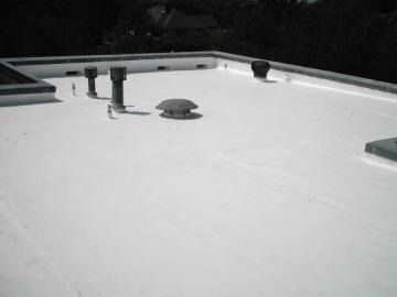 White flat rooftop with vents and a skylight at night