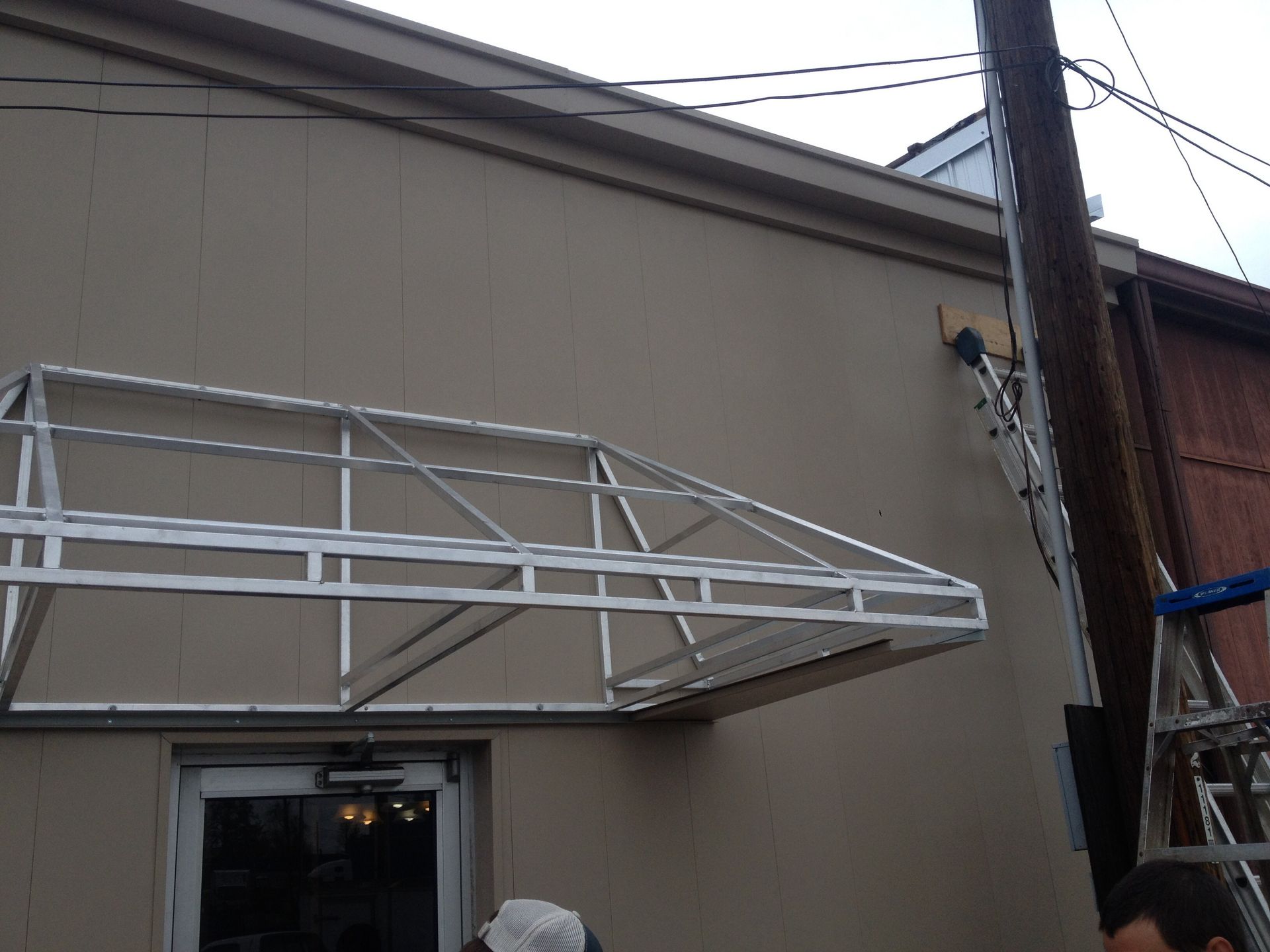 White metal awning frame mounted above a window on a beige building exterior