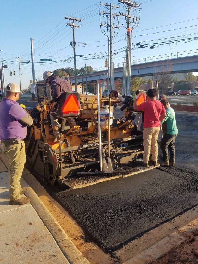 Workers using shovels to fill and smooth a pothole with patching material. Workers using shovels to fill and smooth a pothole with patching material.