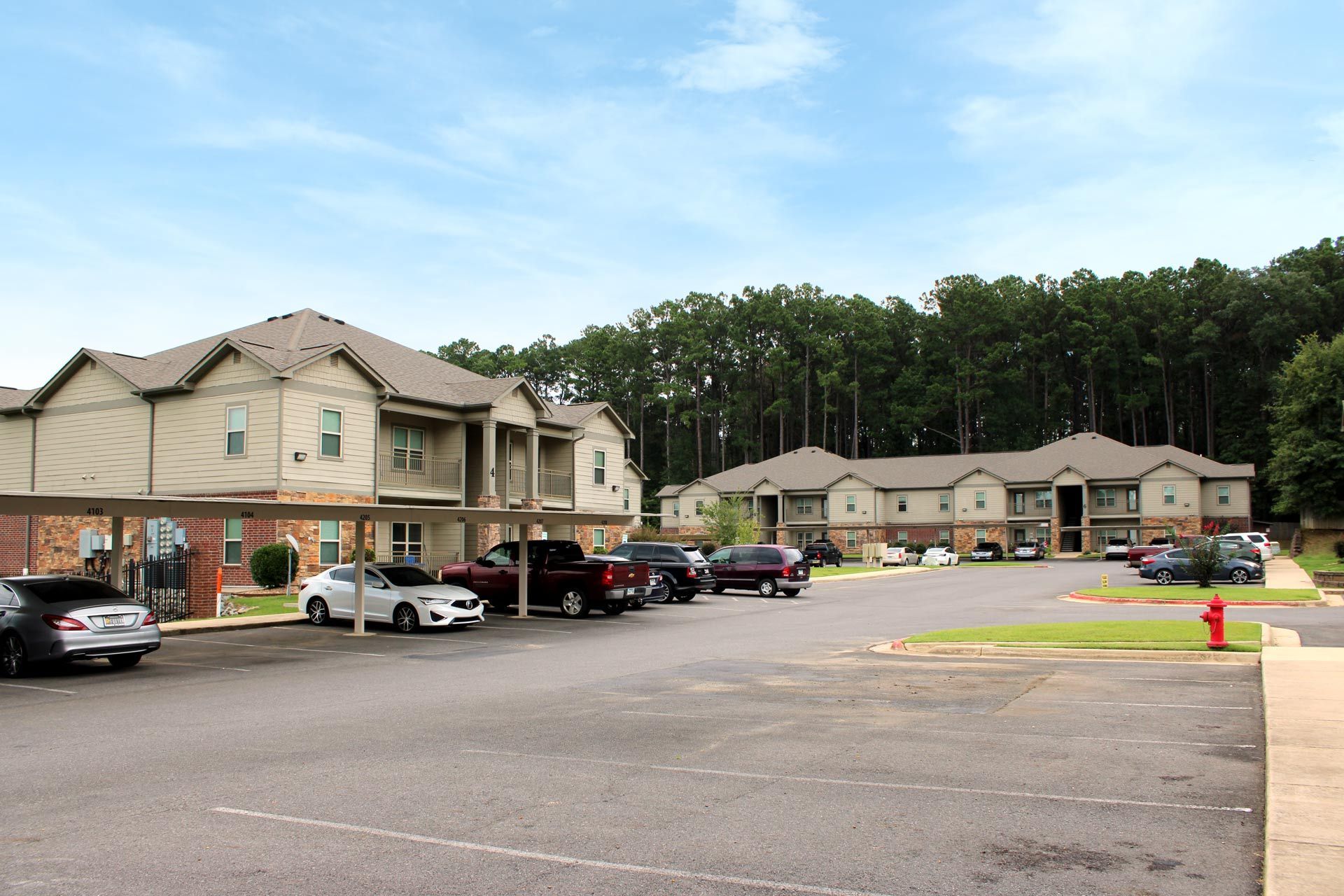 A parking lot with cars parked in front of a apartment building.