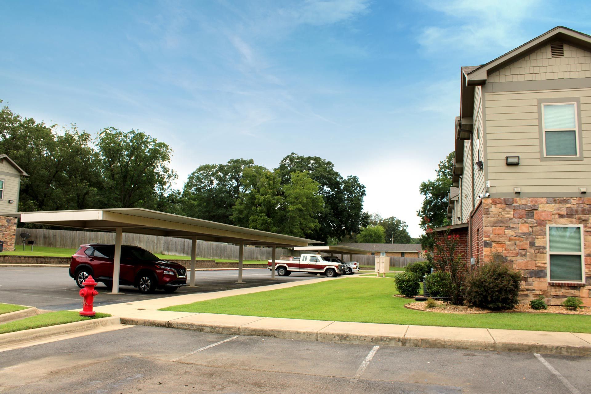 A red car is parked under a covered parking lot