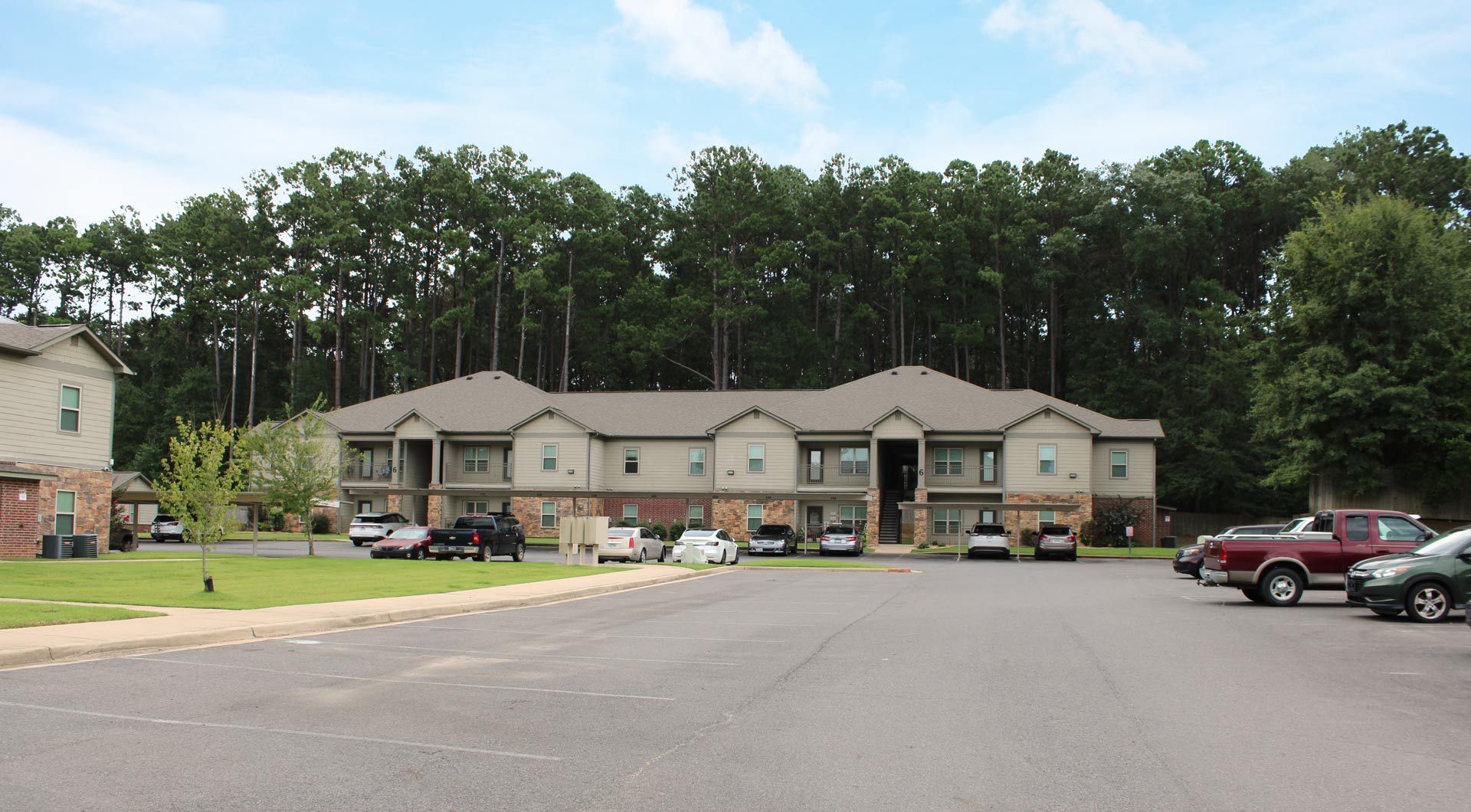A large apartment building with a lot of cars parked in front of it