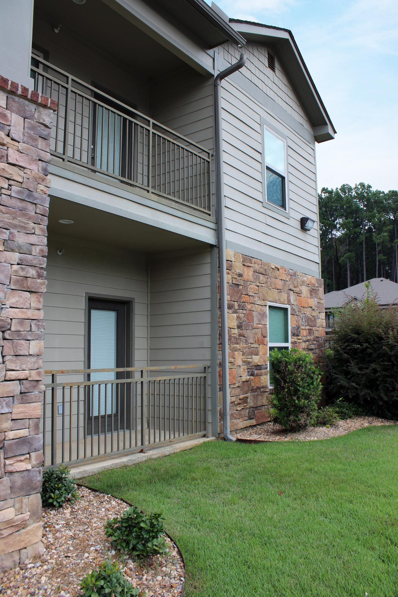 A large apartment building with a balcony and a stone wall.