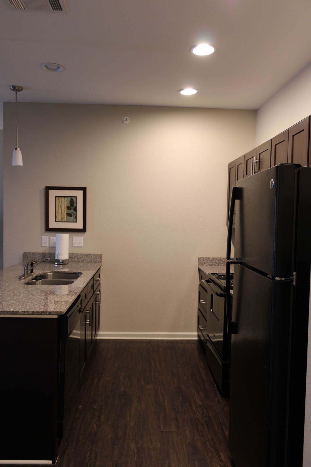 A kitchen with a black refrigerator , stove , sink and cabinets.