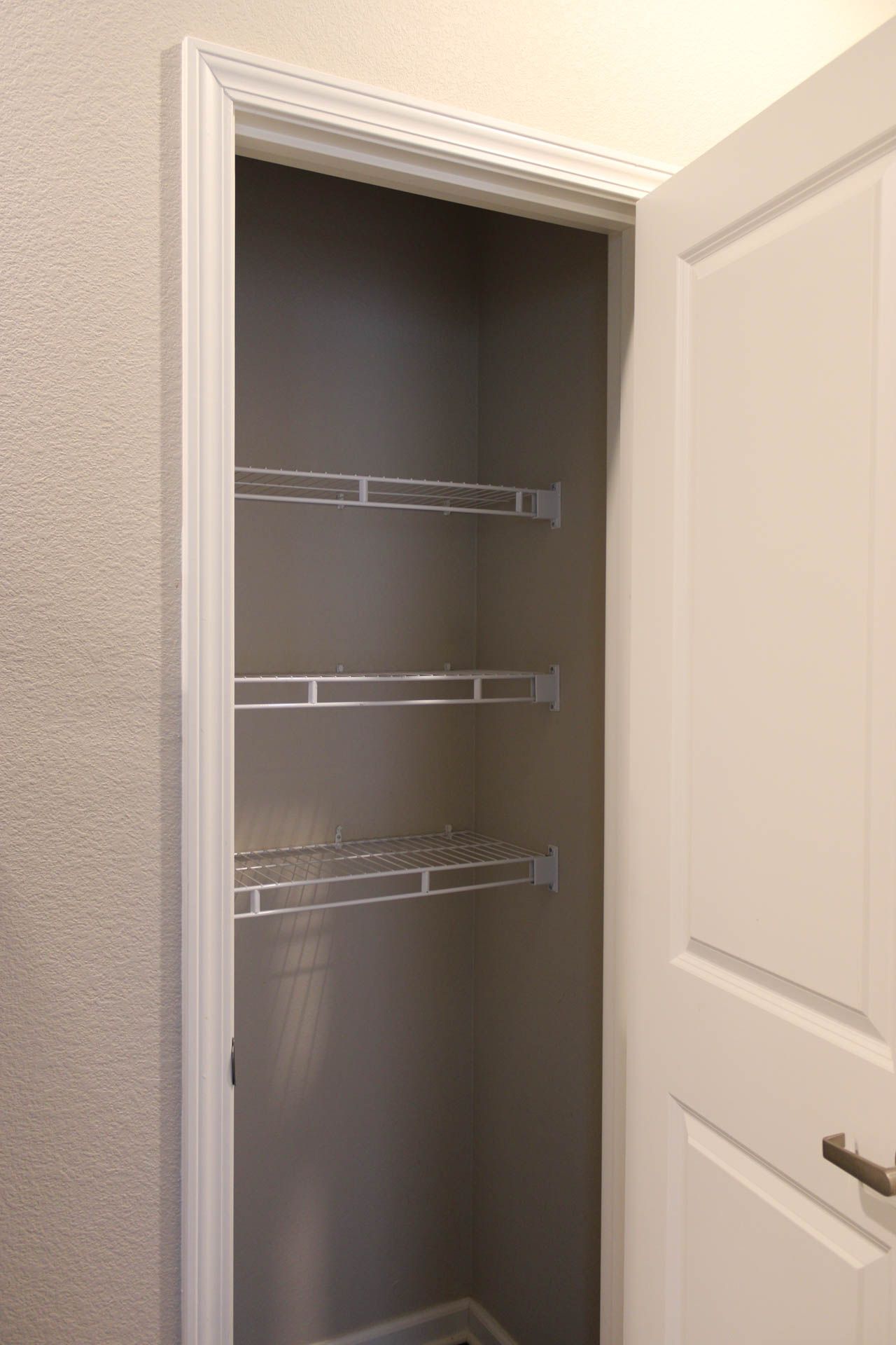 A closet with a door open and shelves in it.