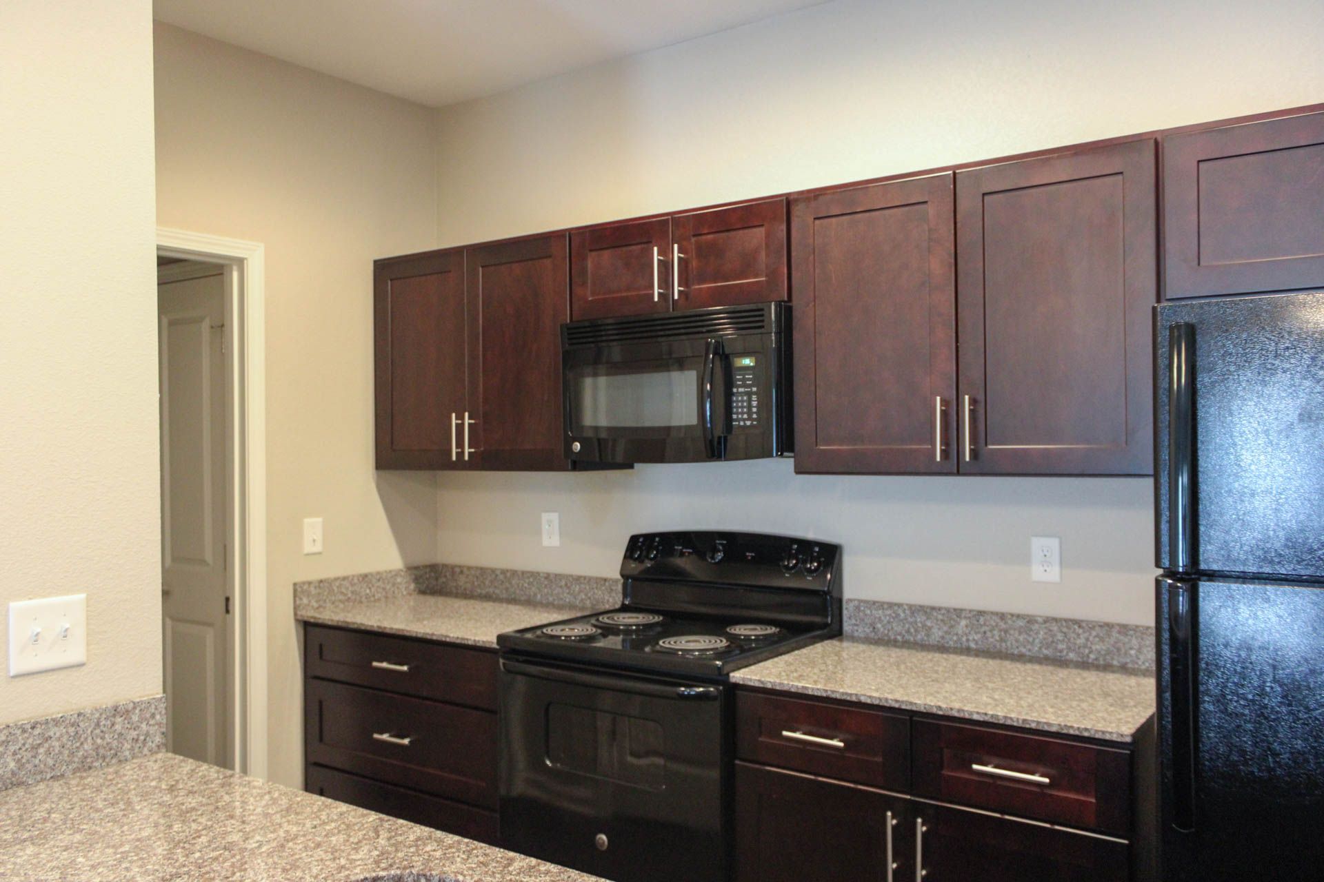 A kitchen with a stove , refrigerator , microwave and cabinets