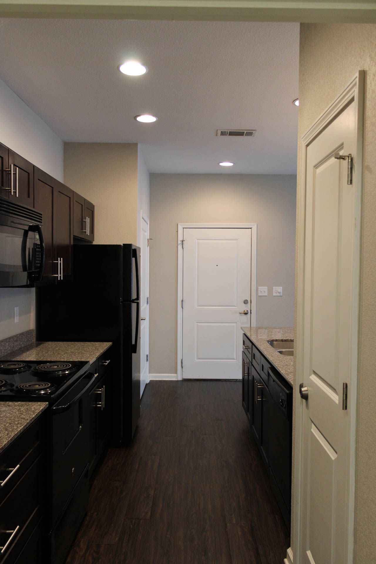 A kitchen with a black refrigerator , stove , sink and microwave.