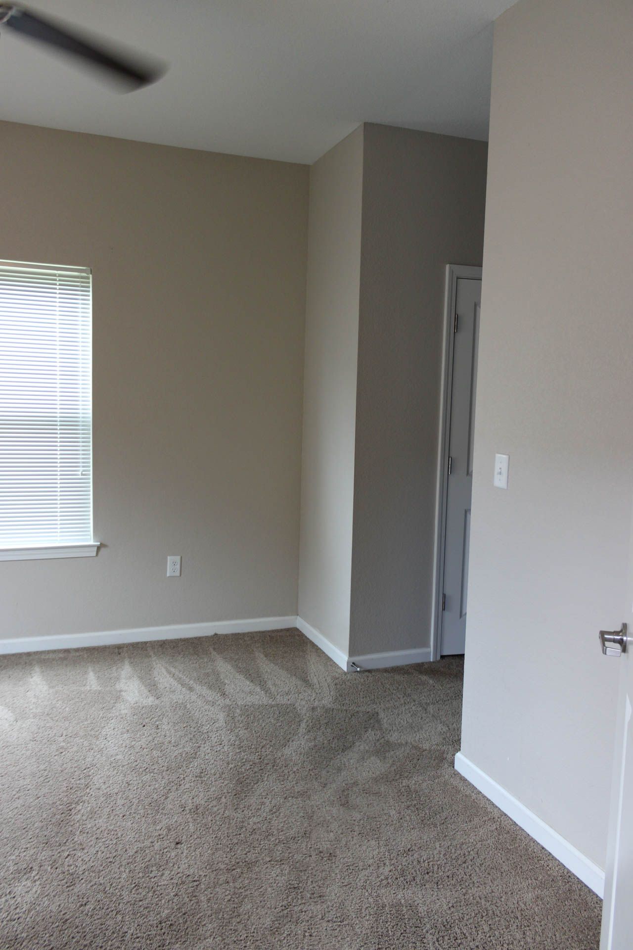 An empty bedroom with a ceiling fan and a window.