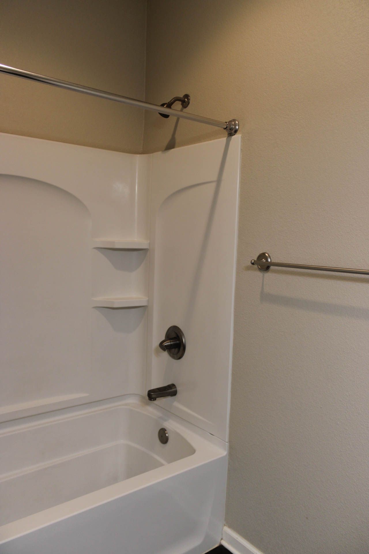 A bathroom with a bathtub , shower , and towel rack.