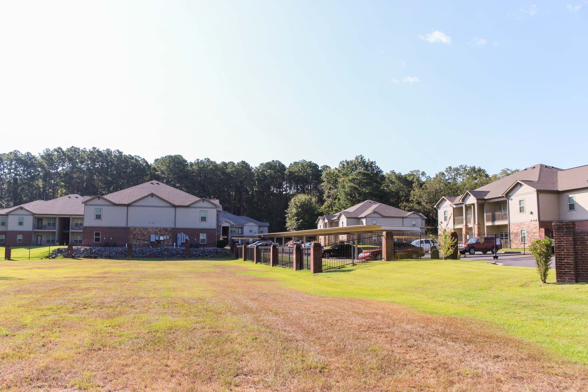 A row of apartment buildings with a large grassy field in front of them.