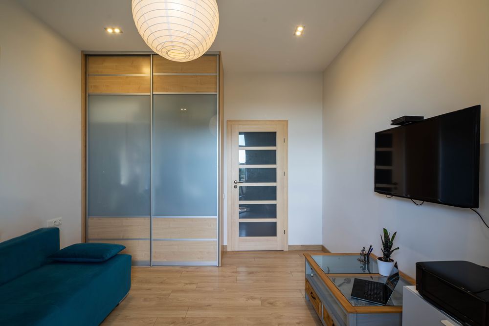 Modern Living Room With Teal Sofa, Frosted Wardrobe and Wall TV — MATV Systems Australia Pty Ltd in Wickham, NSW