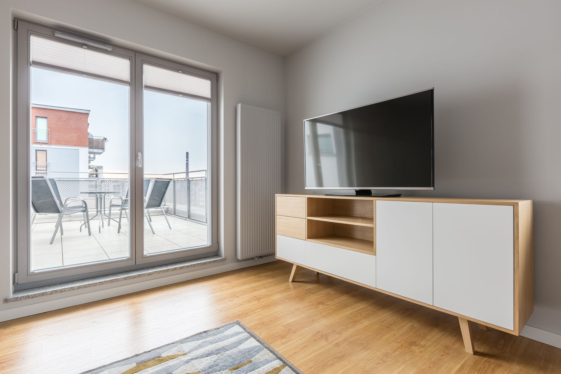 Bright living room with a TV, low cabinet, large windows, and a balcony view. — MATV Systems Australia Pty Ltd in Wickham, NSW