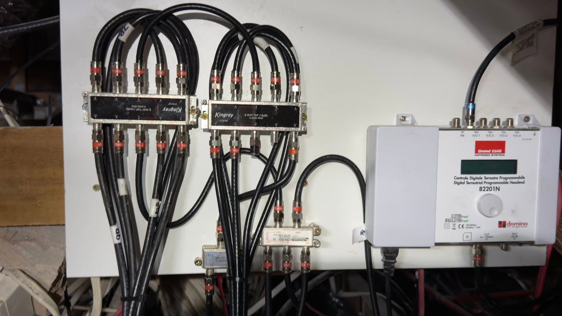 Electrical control panel with black cables connected to relays and a white circuit box on a wall. — MATV Systems Australia Pty Ltd in Wickham, NSW