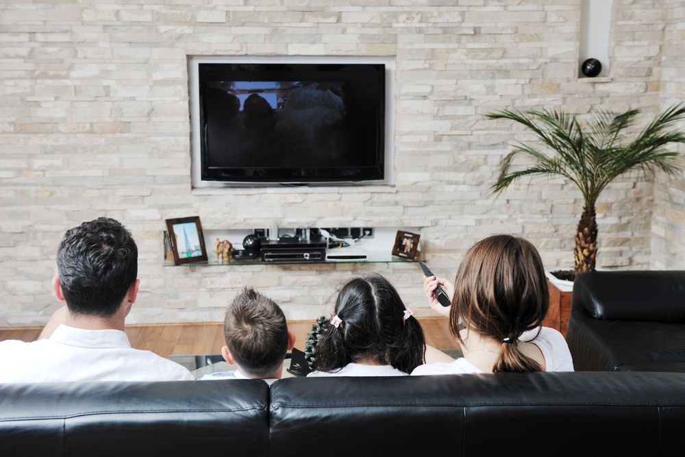 People Sitting on a Couch Watching TV in a Living Room — MATV Systems Australia Pty Ltd in Wickham, NSW