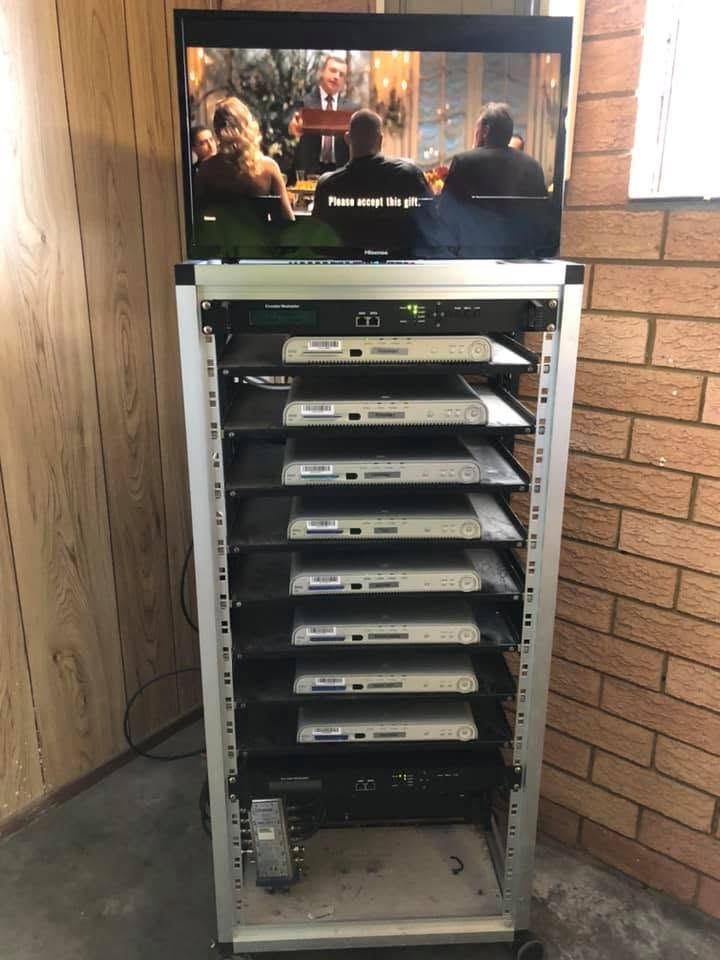 Open AV rack with stacked equipment below a TV showing a scene in a room corner — MATV Systems Australia Pty Ltd in Wickham, NSW