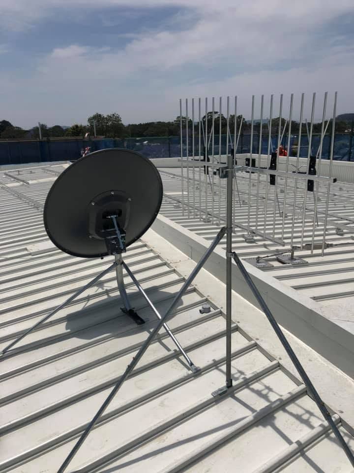 Satellite dish on a rooftop with metal antenna frames and city skyline in the background — MATV Systems Australia Pty Ltd in Wickham, NSW