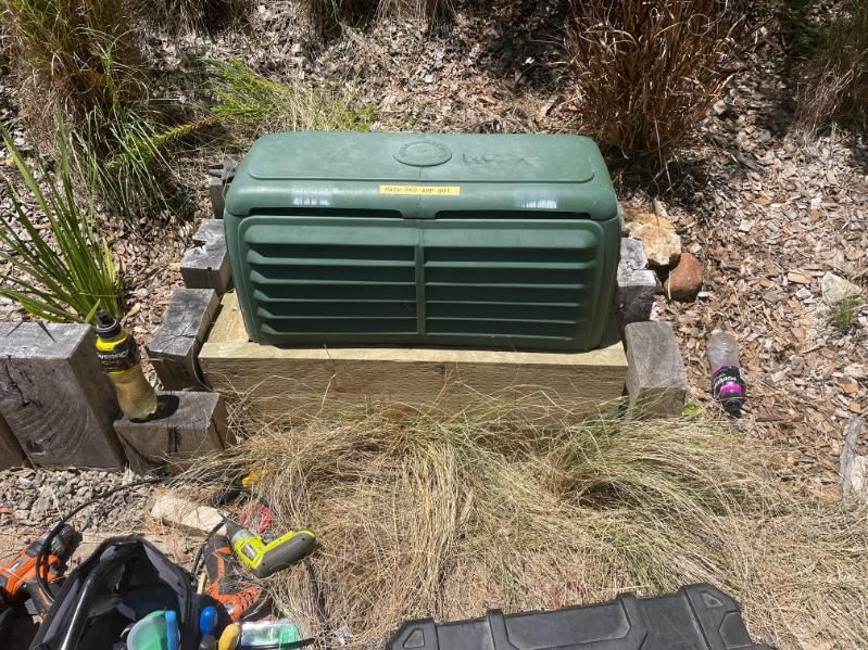 A Green Box Is Sitting on Top of A Wooden Platform in The Grass — MATV Systems Australia Pty Ltd in Sydney, NSW