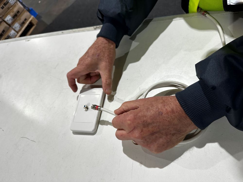 A Man Is Working on A Device on A Table — MATV Systems Australia Pty Ltd in Wickham, NSW